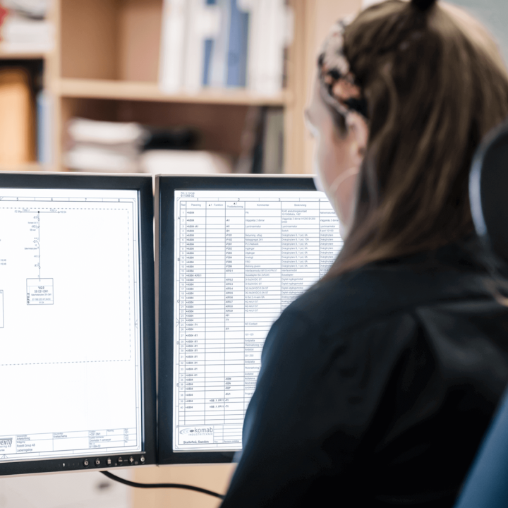 Woman looking at two computer screens with construction drawing