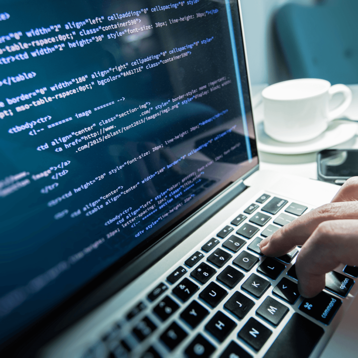 Computer screen with program code. A coffee cup and phone in the background